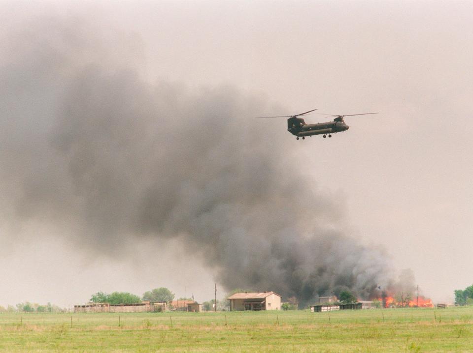A National Guard helicopter flies past the burning Branch Davidian compound on April 19, 1993.