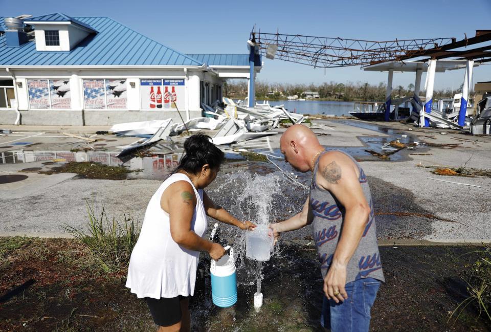 Danny, derecha, y Gina Holland llenan envases con agua el jueves 11 de octubre de 2018 en Parker, Florida, luego del paso del huracán Michael. (AP Foto/David Goldman)