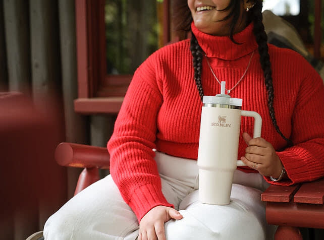 model holding white Stanley tumbler cup with straw