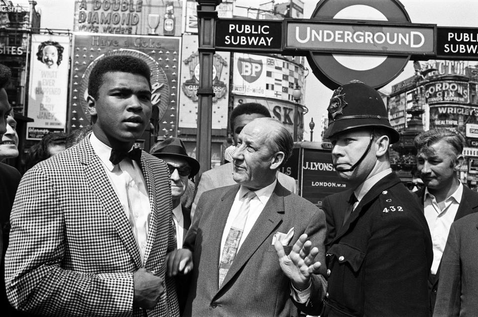 Cassius Clay aka (Muhammad Ali left) with Dave Edgar, Jack Solomon's representative who is looking after him in London, takes a look round the Piccadilly Circus area,and a Policeman asks them to move on, 27th May 1963. (Photo by Arthur Sidey & Charles Ley/Mirrorpix/Getty Images)