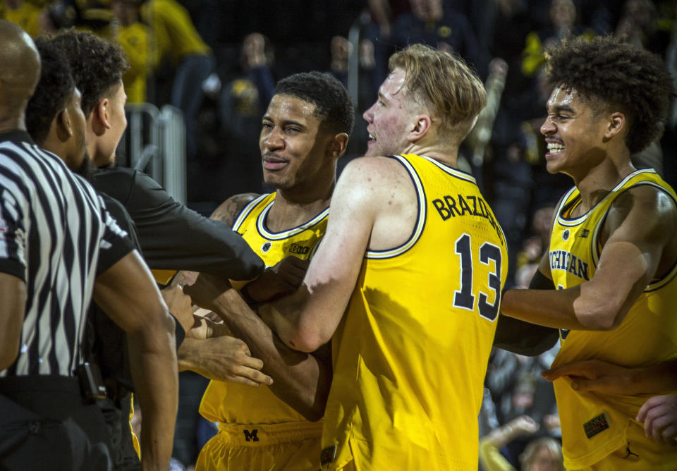 Michigan guard Charles Matthews, center, celebrates his game-winning buzzer-beater with forward Ignas Brazdeikis (13) and guard Jordan Poole, right, after an NCAA college basketball game against Minnesota at Crisler Center in Ann Arbor, Mich., Tuesday, Jan. 22, 2019. Michigan won 59-57. (AP Photo/Tony Ding)