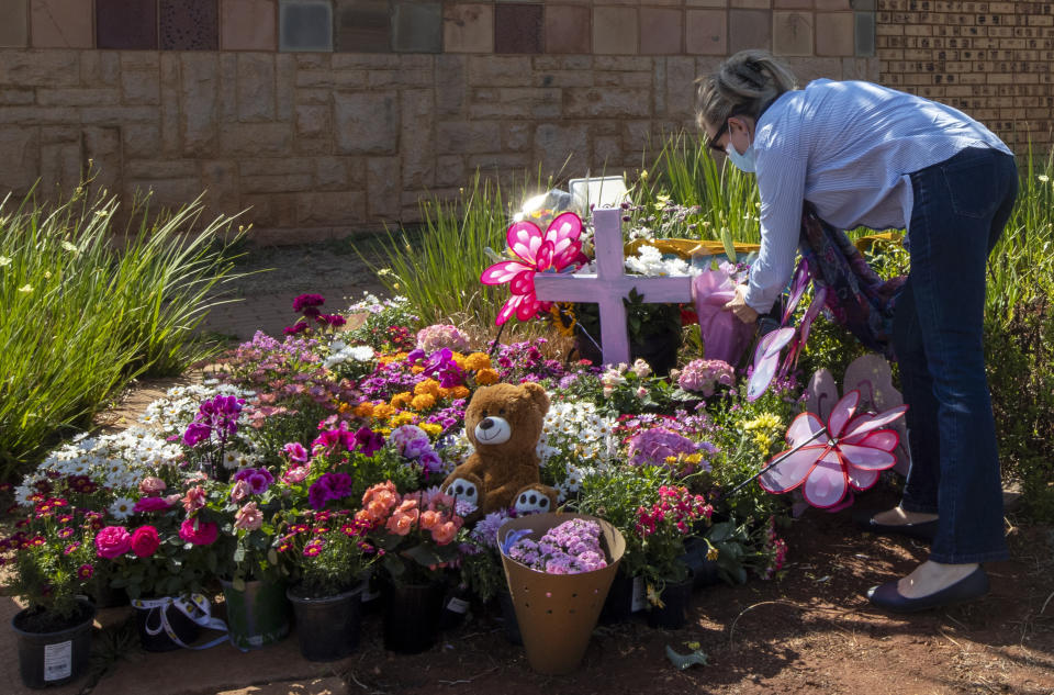 Christine Wright leaves flowers outside the complex where the Dickason family lived prior to their emigration to New Zealand, in Pretoria, South Africa, Thursday, Sept. 23, 2021. People in the town of Timaru are planning an evening vigil outside the home of three young girls who were killed last week in a crime that shocked New Zealand. The girls' mother Lauren Dickason has been charged with their murder. (AP Photo/Themba Hadebe)