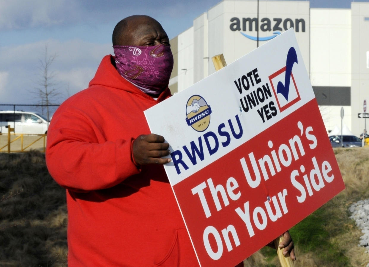 Michael Foster of the Retail, Wholesale and Department Store Union holds a sign outside an Amazon facility where labor is trying to organize workers in Bessemer, Ala., on Feb. 9, 2021. On Tuesday, Jan. 11, 2022, the National Labor Relations Board said that Amazon workers in the Bessemer facility will vote by mail in February 2022 in a re-run election to decide whether or not to unionize. (AP Photo/Jay Reeves, File)