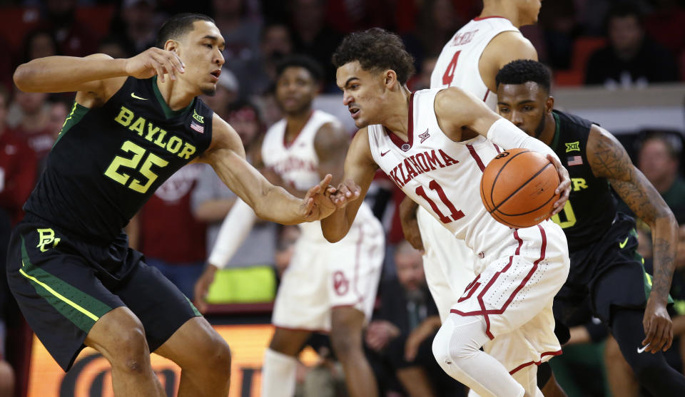 Oklahoma guard Trae Young (11) drives between Baylor forward Tristan Clark (25) and guard Tyson Jolly, right, during the first half of an NCAA college basketball game in Norman, Okla., Tuesday, Jan. 30, 2018. (AP Photo/Sue Ogrocki)