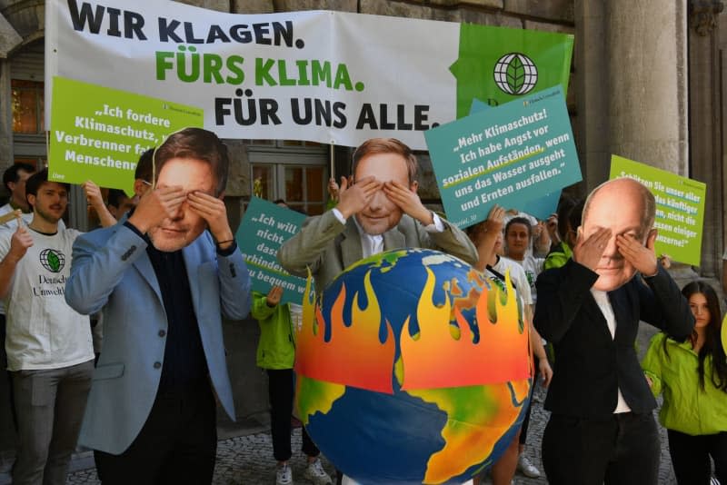 Activists from Deutsche Umwelthilfe (DUH) protest with masks showing the leading members of the traffic light government in front of the Berlin Higher Administrative Court. Paul Zinken/dpa