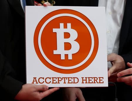 A bitcoin sign is held in Hong Kong February 28, 2014. REUTERS/Bobby Yip/Files