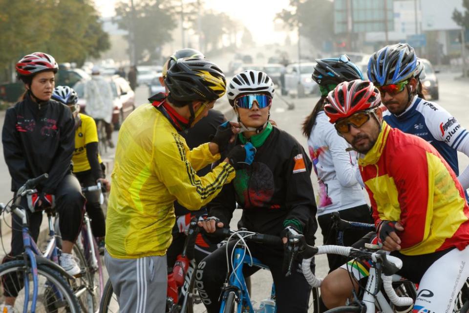 Ahmad Navid, a member of the Afghan national cycling team, helps Rukhsar Habibzai, the 22-year-old coach of the women’s national cycling team, during their daily practice on the outskirts of Kabul, Afghanistan, in October 2020.