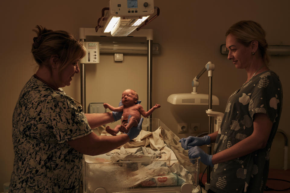 A medic holds a newborn baby in a city hospital in Mykolaiv, the site of heavy battles with Russian forces, Ukraine, Thursday, Nov. 3, 2022. (AP Photo/LIBKOS)