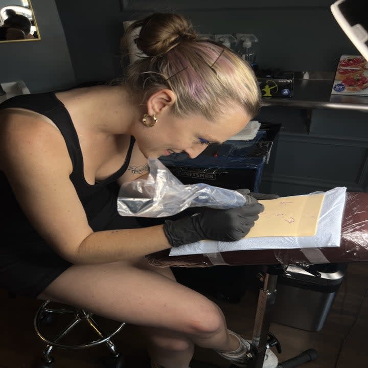 Syd Robinson tattooing her stencil.