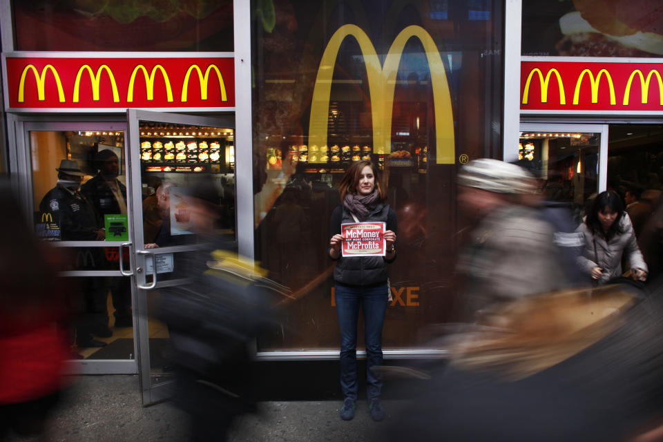 A member of 'MoveOn' holds up a poster during a protest in front of McDonald's restaurant in Times Square, New York, December 4, 2013. MoveOn members will be protesting at McDonald's locations in five cities - Seattle, San Francisco, New York, Los Angeles, and Chicago, and delivering a petition started by "Low Pay is Not Okay". The petition, which is addressed to McDonald's, Burger King, Taco Bell, KFC, Pizza Hut, Domino's, Papa John's, and Subway, and has the support of nearly 50,000 MoveOn members, demands a $15/hour living wage for all fast food workers. REUTERS/Eduardo Munoz (UNITED STATES - Tags: CIVIL UNREST FOOD SOCIETY TPX IMAGES OF THE DAY)