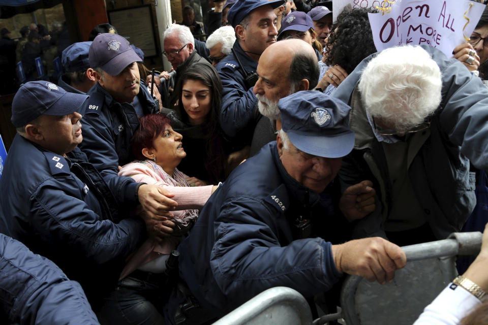 Protesters break the police barriers as they demonstrate against the closing of a crossing point straddling a United Nations-controlled buffer zone in divided capital Nicosia, Cyprus, Saturday, Feb. 29, 2020. Around 200 people gathered at the Ledra Street crossing point to voice their opposition to its closing. The Cyprus government said it closed the Ledra Street crossing point along with three others to help with efforts to prevent the possible spread of a new COVID-19 virus either to the breakaway, Turkish Cypriot north or the internationally recognized, Greek Cypriot south. (AP Photo/Petros Karadjias)