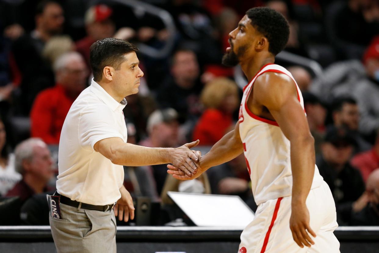 Cincinnati Bearcats head coach Wes Miller high fives guard David DeJulius (5) as he returns to the bench in the second half of the NCAA American Athletic Conference basketball game between the Cincinnati Bearcats and the Memphis Tigers at Fifth Third Arena in Cincinnati on Tuesday, Feb. 15, 2022. The Tigers rode a halftime lead to an 81-74 win over the Bearcats. 