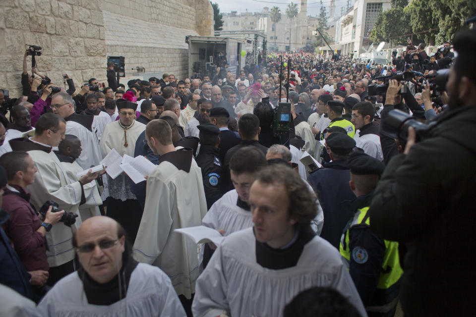 Christians celebrate the arrival of Archbishop Pierbattista Pizzaballa, the top Roman Catholic cleric in the Holy Land, center, after he crossed an Israeli military checkpoint from Jerusalem ahead of midnight Mass at the Church of the Nativity, traditionally recognized by Christians to be the birthplace of Jesus Christ, in the West Bank city of Bethlehem, Monday, Dec. 24, 2018. Palestinians are preparing to host pilgrims from around the world in celebrating Christmas in the West Bank city of Bethlehem. (AP Photo/Nasser Nasser)