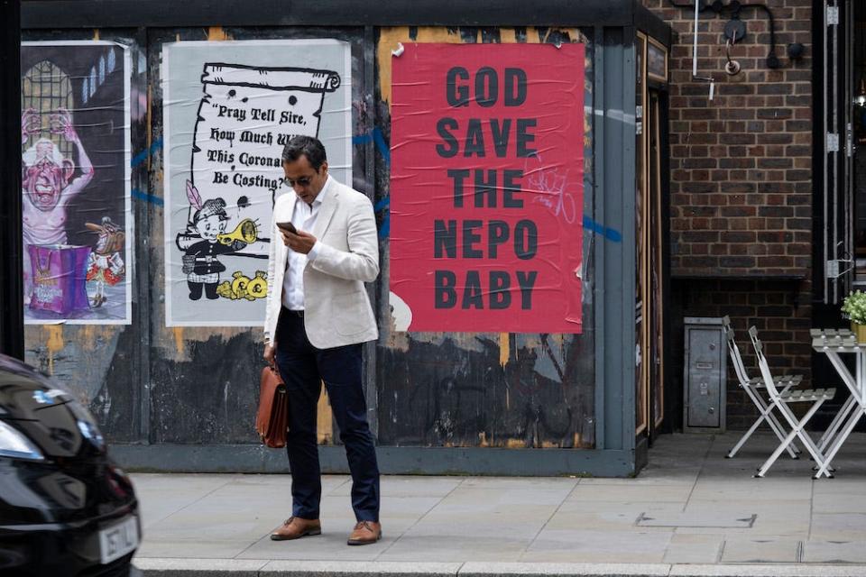 A red poster with black text, pasted to a wall, reads "God save the nepo baby" in east London in May 2023.