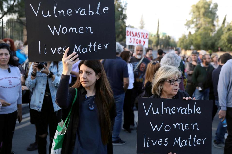 People attend hold placards during a public gathering in memory of the victims (REUTERS)