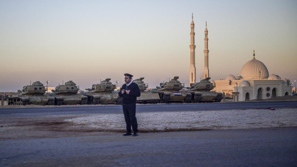 FILE - A police officer stands on the side of the road near a row of tanks as the motorcade of Secretary of State Mike Pompeo drives past the newly-inaugrated Al-Fattah Al-Alim mosque, in Egypt's New Administrative Capital, east of Cairo, Thursday, Jan. 10, 2019. Egypt’s president has ordered his administration to start moving its offices next month to a sprawling new administrative capital in the desert outside Cairo. President Abdel Fattah el-Sissi has directed the government to begin working from the new complex starting Dec. 1, 2021. (Andrew Caballero-Reynolds/Pool Photo via AP, File)