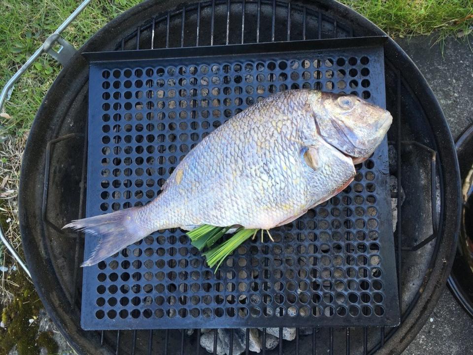 Scup stuffed with greens on the grill.