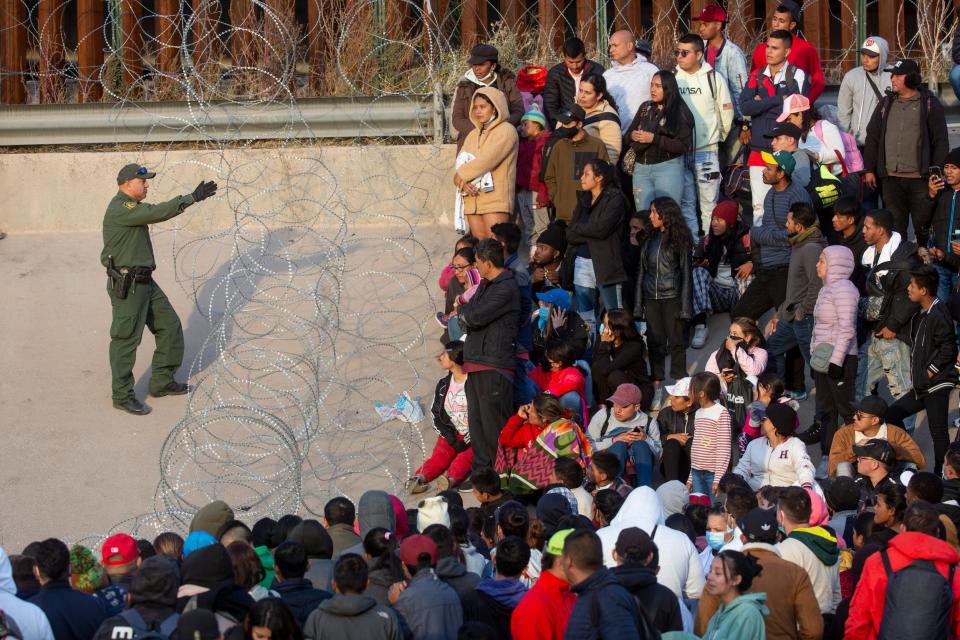 Migrants crossed the Rio Grande and approach concertina wire placed by the Texas National Guard to ask a Border Patrol agent when they will be allowed to be processed by Customs and Border Protection to seek asylum in El Paso, Texas on Dec. 20, 2022