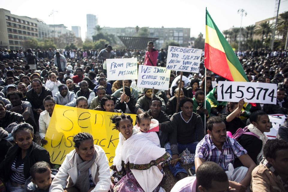 African migrants hold signs during a protest in Tel Aviv