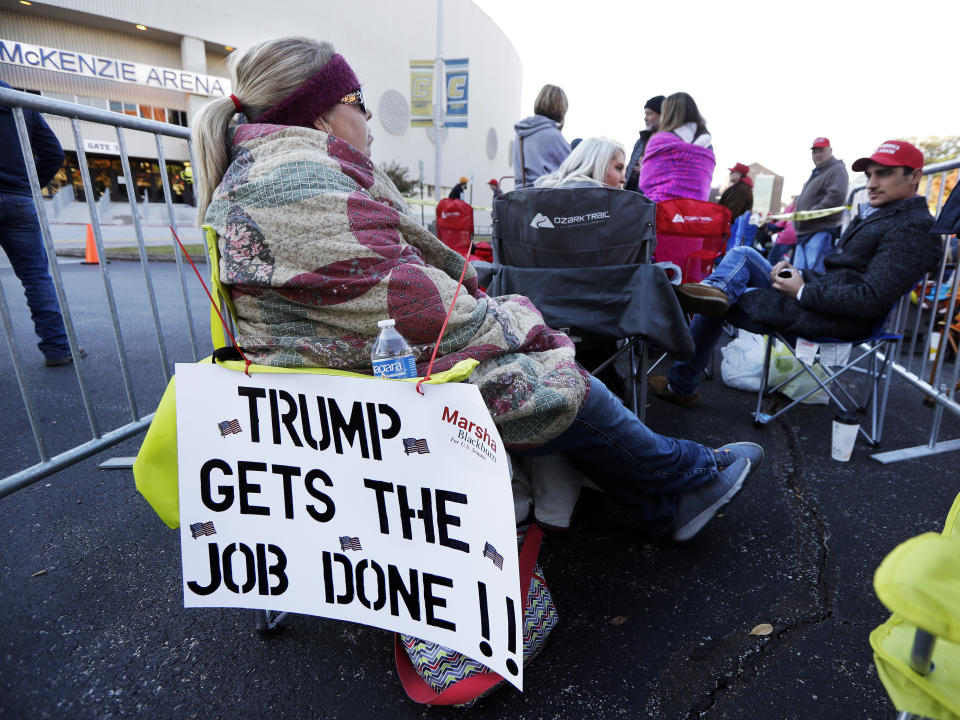 Casey Mchone aguarda en la McKenzie Arena el comienzo de un acto con el presidente Donald Trump en Chattanooga, Tennessee, domingo 4 de noviembre de 2018. Su cartel dice "Trump realiza la tarea". (AP Foto/Mark Humphrey)