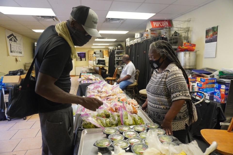 Georgia Fair, right, a volunteer with the Neighborhood House food distribution program run by the Beta Pi Chapter of Omega Psi Phi Fraternity Inc., helps a man recently at the program that is open 11:30 a.m.-1 p.m. Sunday through Friday at 739 NW Fifth Ave.
(Credit: Photo provided by Voleer Thomas)