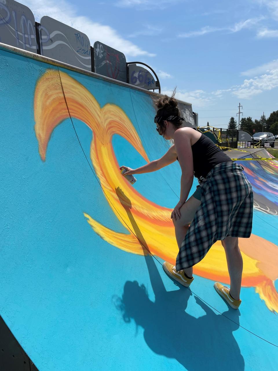 Alecia Svensen of Grayling paints a Dragon Coy Fish, one of the new murals representing rebirth, at the Gaylord Ramp Park.