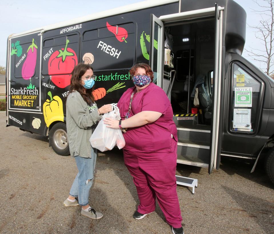 Azella Markgraf, mobile grocery market coordinator, hands items to Kayla McMillen outside of StarkFresh's mobile market Thursday at the Wellness Village at Midway in Canton.