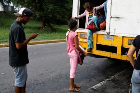 A woman tries to get off a cargo truck used as public transportation in Valencia, Venezuela July 11, 2018. REUTERS/Marco Bello