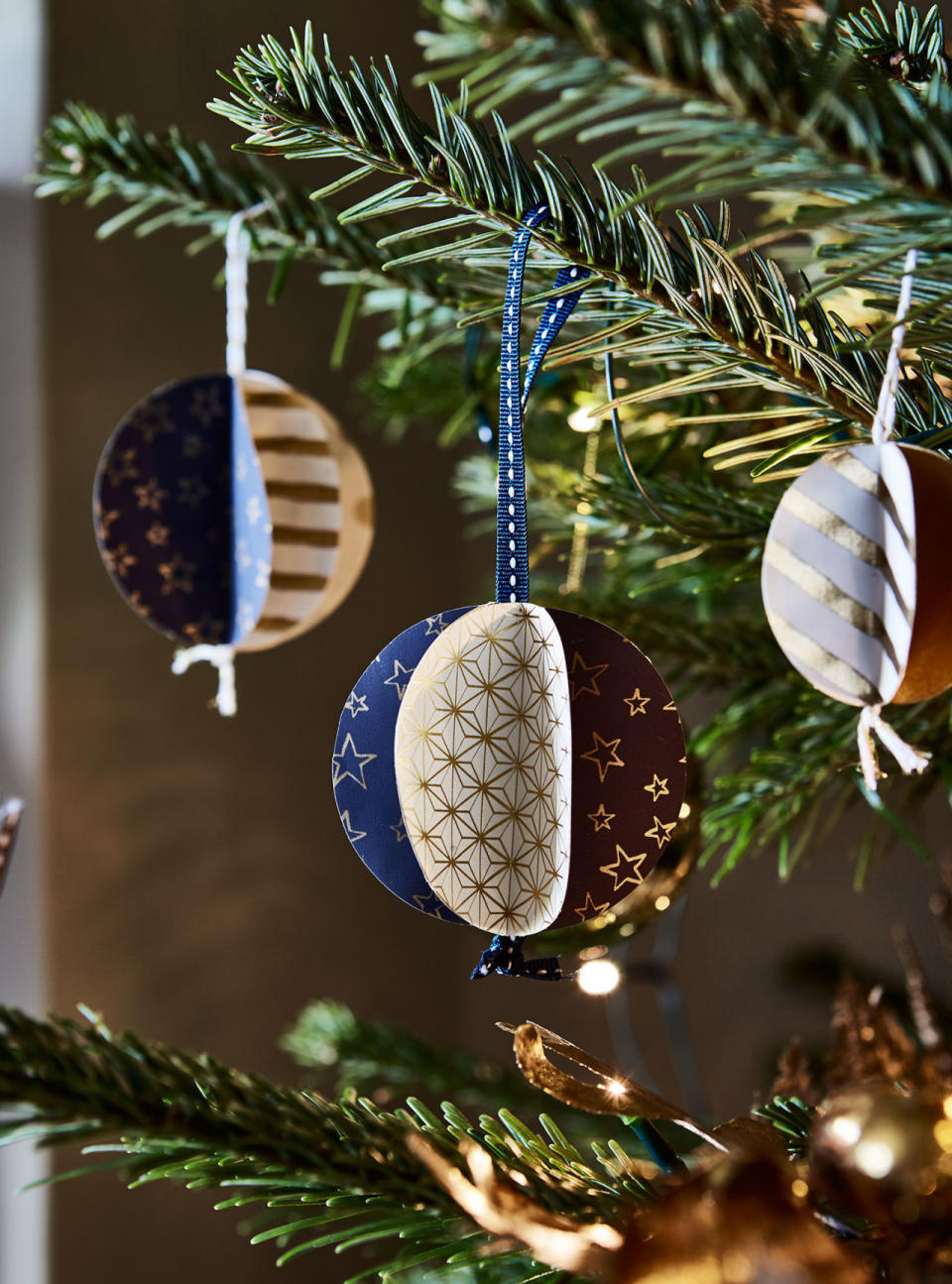 <p>Make each bauble by </p><p><strong>1.</strong> Cutting out six circles from wrapping paper. </p><p><strong>2.</strong> Fold each in half and glue the halves together. </p><p><strong>3. </strong>Place ribbon or twine knotted at one end in the centre before gluing on the last circle. </p><p>• Paper, from a selection, <a rel="nofollow noopener" href="https://www.paperchase.co.uk/?gclid=EAIaIQobChMI4bmpl4fQ1wIVlyWBCh1orQYjEAAYASAAEgIGZfD_BwE" target="_blank" data-ylk="slk:Paperchase;elm:context_link;itc:0;sec:content-canvas" class="link ">Paperchase</a>, <a rel="nofollow noopener" href="https://www.dotcomgiftshop.com/?gclid=EAIaIQobChMIrIjGoYfQ1wIVViOBCh1YNwovEAAYASAAEgLIRPD_BwE" target="_blank" data-ylk="slk:Dot Com Gift Shop;elm:context_link;itc:0;sec:content-canvas" class="link ">Dot Com Gift Shop</a> and <a rel="nofollow noopener" href="https://www.coxandcox.co.uk/" target="_blank" data-ylk="slk:Cox & Cox;elm:context_link;itc:0;sec:content-canvas" class="link ">Cox & Cox</a>. </p><p>• Ribbon and twine, from a selection, <a rel="nofollow noopener" href="https://www.pipii.co.uk/" target="_blank" data-ylk="slk:Pipii;elm:context_link;itc:0;sec:content-canvas" class="link ">Pipii</a> and <a rel="nofollow noopener" href="https://janemeans.com/" target="_blank" data-ylk="slk:Jane Means;elm:context_link;itc:0;sec:content-canvas" class="link ">Jane Means</a>.</p>