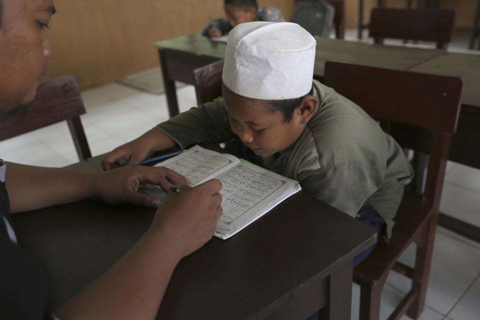 A Muslim student reads the Quran at an Islamic boarding school in Tenggulun, East Java, Indonesia, on Saturday, April 27, 2019. The school is part of Ali Fauzi's Circle of Peace Foundation, which Fauzi created in a bid to combat violent extremism. (AP Photo/Tatan Syuflana)