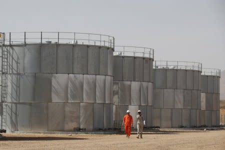 Workers walk past storage tanks at Tullow Oil's Ngamia 8 drilling site in Lokichar, Turkana County, Kenya, February 8, 2018. Picture taken February 8, 2018. REUTERS/Baz Ratner