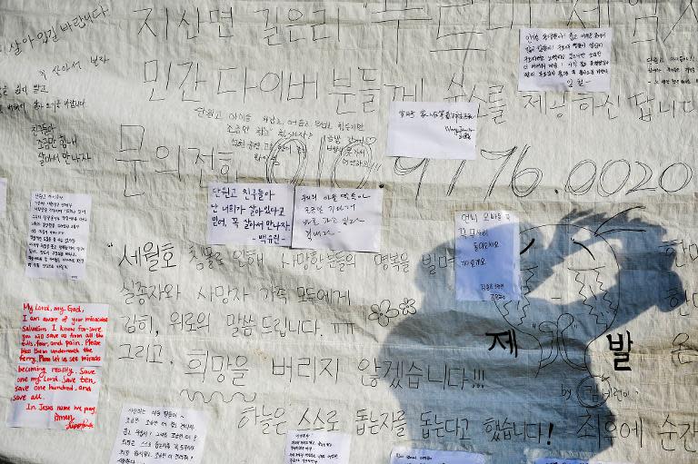 A person takes photos of messages written for missing passengers aboard a capsized ferry at a harbour in Jindo on April 19, 2014