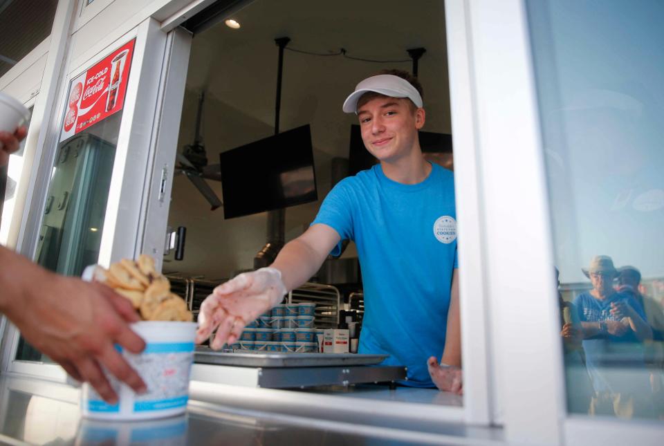 Collin Tewes serves an overstuffed bucket of cookies for a hungry fairgoer at Barksdale Cookies in 2021.