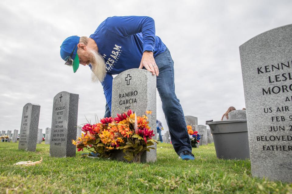 Kevin Gossett wipes behind a headstone at the Coastal Bend Veteran's Cemetery on Tuesday, Nov. 28, 2023, in Corpus Christi, Texas. Gossett volunteered to clean headstones with TAMUCC staff.