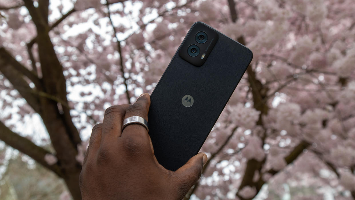  The Moto G Power 5G 2024 in hand with cherry blossoms behind. 