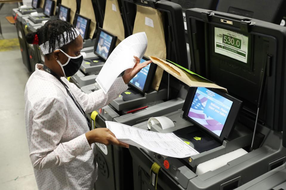 A Miami-Dade election worker feeds ballots into a voting machines during an accuracy test at the Miami-Dade Election Department headquarters on Oct. 14, 2020 in Doral, Florida.