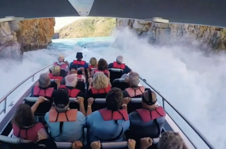 A boat of tourists on a boat passing Horizontal Falls with waves splashing. 