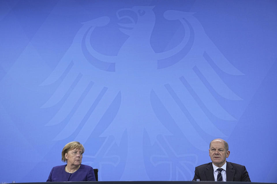 German Chancellor Angela Merkel, left, and Olaf Scholz, Federal Finance Minister, meet the media in Berlin, Thursday, Nov. 18, 2021. German lawmakers have approved new measures to rein in record coronavirus infections after the head of Germany’s disease control agency warned the country could face a “really terrible Christmas.” The measures passed in the Bundestag on Thursday includes requirements for employees to prove they are vaccinated, recovered from COVID-19 or have tested negative for the virus in order to access communal workplaces. (Michael Kappeler, Pool via AP)