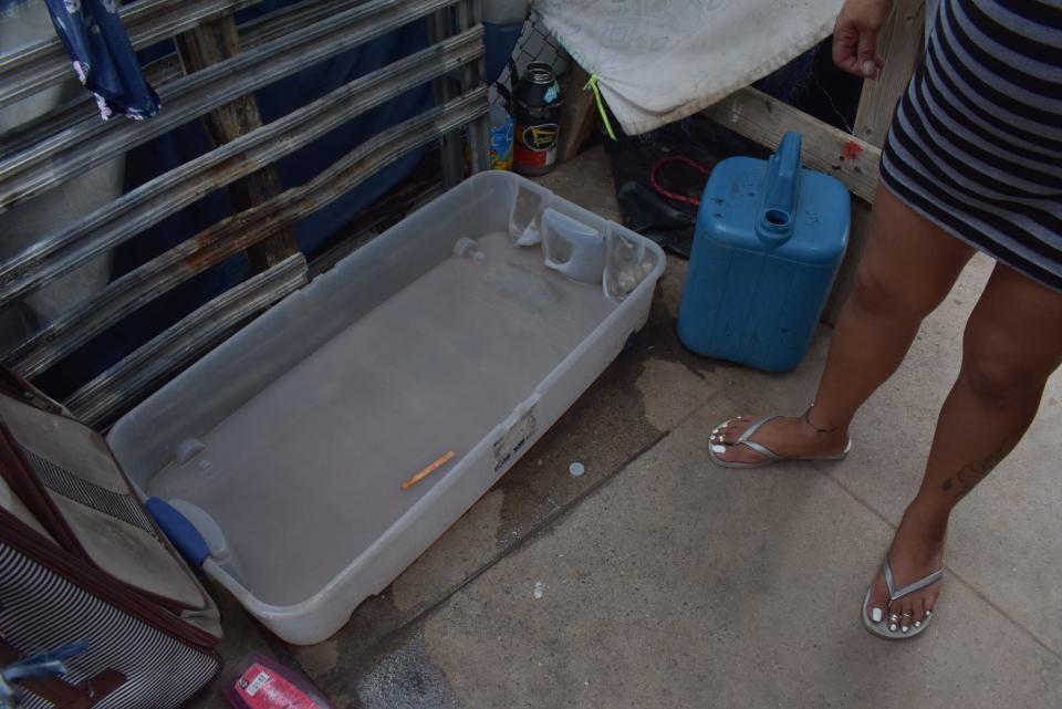 A clear plastic container catches the water from the makeshift shower Bianca Farias built in the Zone, a blocks-large homeless encampment near Phoenix's Human Services Campus.