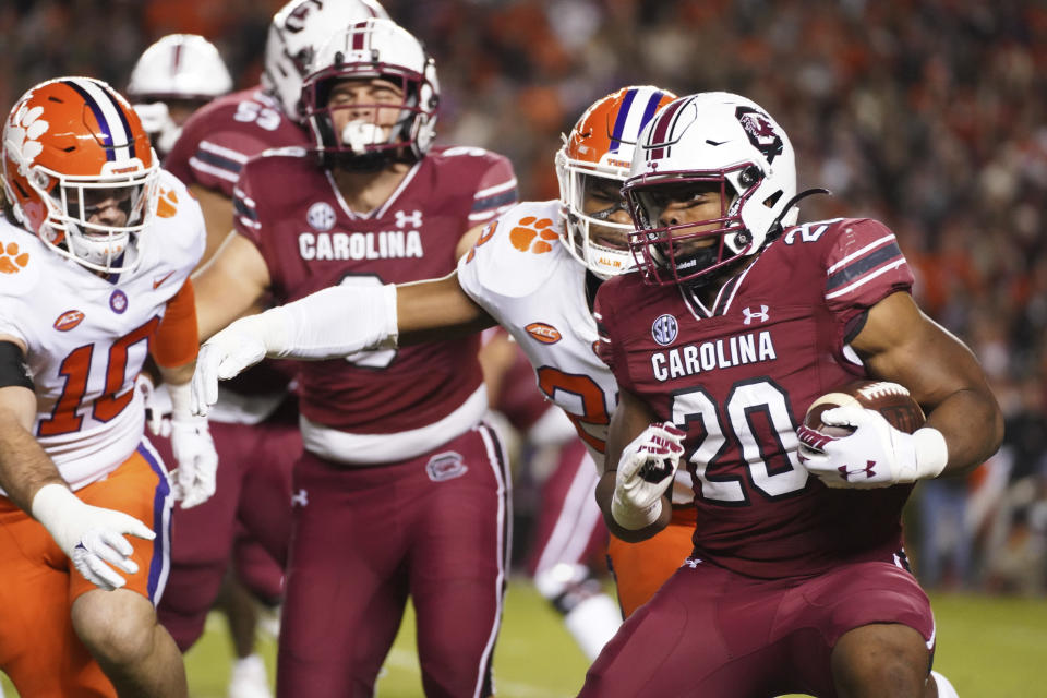 South Carolina running back Kevin Harris (20) runs with the ball against Clemson's Trenton Simpson (22) and Baylon Spector (10) during the first half of an NCAA college football game Saturday, Nov. 27, 2021, in Columbia, S.C. (AP Photo/Sean Rayford)