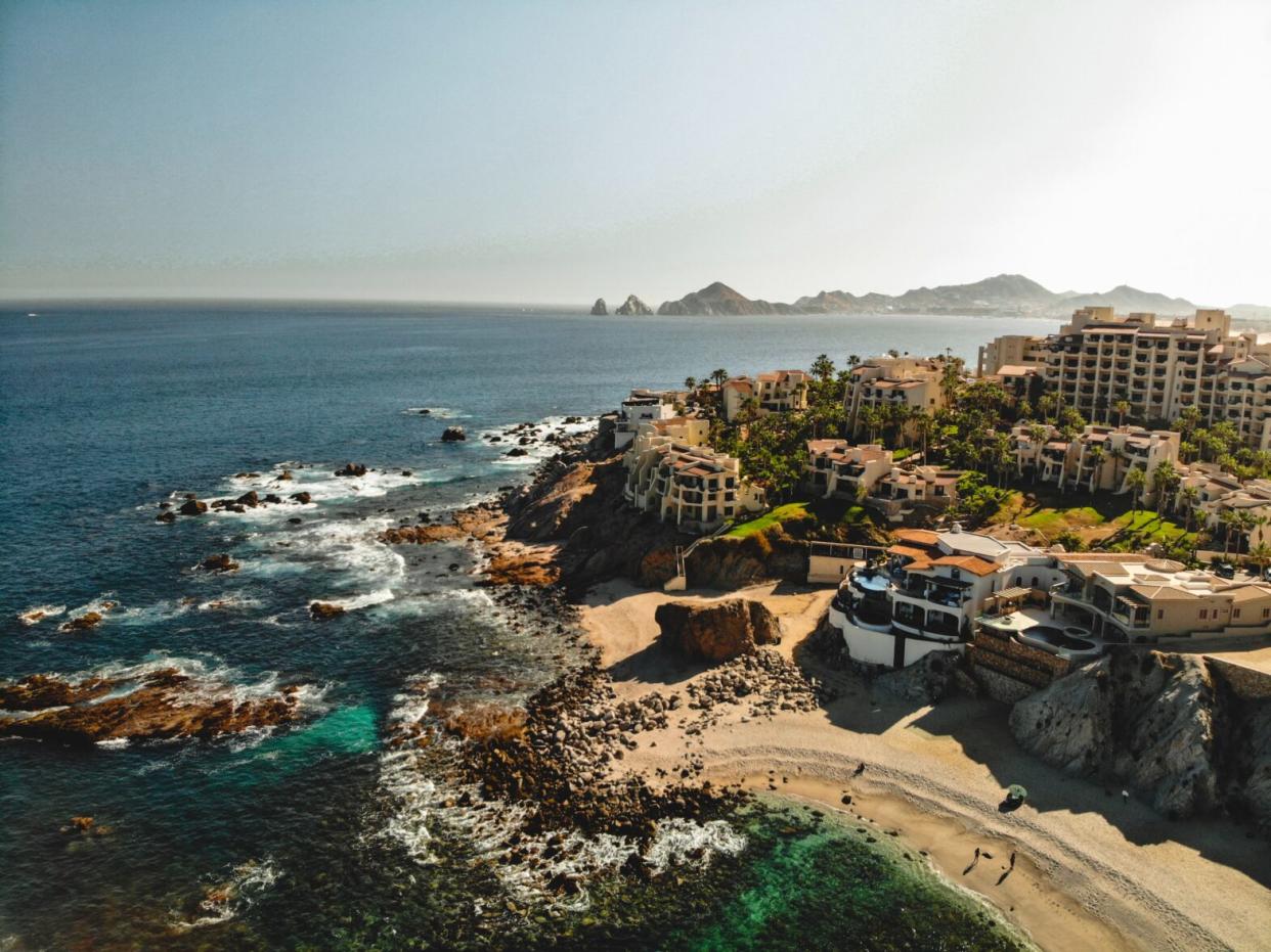 The glimmering coast of Cabo at sunrise surrounded by crashing waves.