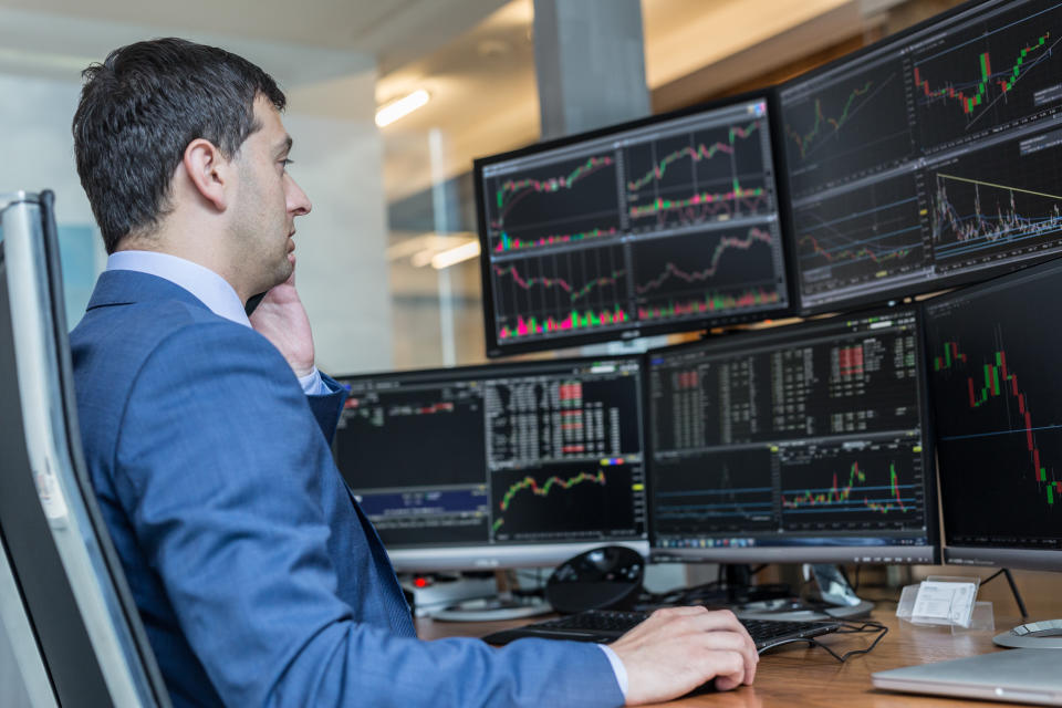 Male stock broker trading online watching charts and data analyses on multiple computer screens. (Source: Getty Creative)