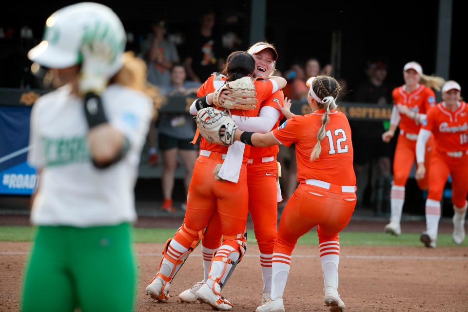 Oklahoma State's Kelly Maxwell (28), center, hugs Taylor Tuck (4), left, as Micaela Wark (12) runs to them after winning the second game between the Oklahoma State Cowgirls (OSU) and the Oregon Ducks in the Stillwater Super Regional of the NCAA softball tournament in Stillwater, Okla., Friday, May 26, 2023. Oklahoma State won 9-0.