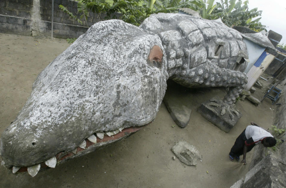 Thierry Atta sweeps the courtyard of his house built in the shape of a crocodile in Ivory Coast's capital Abidjan, September 11, 2008. Atta was an apprentice of the artist Moussa Kalo who designed and built the house but died two months ago. REUTERS/Thierry Gouegnon (IVORY COAST) - RTX8O6X