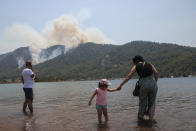 People watch a wildfire burning the forest in Turgut village, near tourist resort of Marmaris, Mugla, Turkey, Wednesday, Aug. 4, 2021. As Turkish fire crews pressed ahead Tuesday with their weeklong battle against blazes tearing through forests and villages on the country's southern coast, President Recep Tayyip Erdogan's government faced increased criticism over its apparent poor response and inadequate preparedness for large-scale wildfires.(AP Photo/Emre Tazegul)