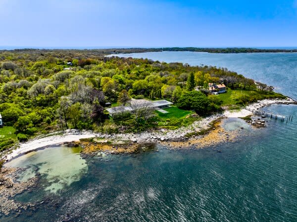 The sprawling property sits on a lush, three-acre waterfront lot overlooking the Connecticut coastline in the distance. Tall trees surrounding the homes ensure ample privacy.