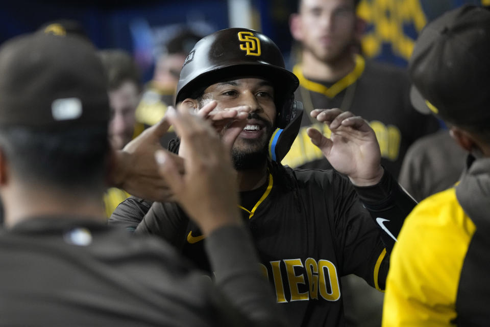 San Diego Padres' Fernando Tatis Jr. is congratulated by teammates in the dugout after scoring on a triple by Jake Cronenworth during the first inning of a baseball game against the Los Angeles Dodgers at the Gocheok Sky Dome in Seoul, South Korea Thursday, March 21, 2024, in Seoul, South Korea. (AP Photo/Ahn Young-joon)