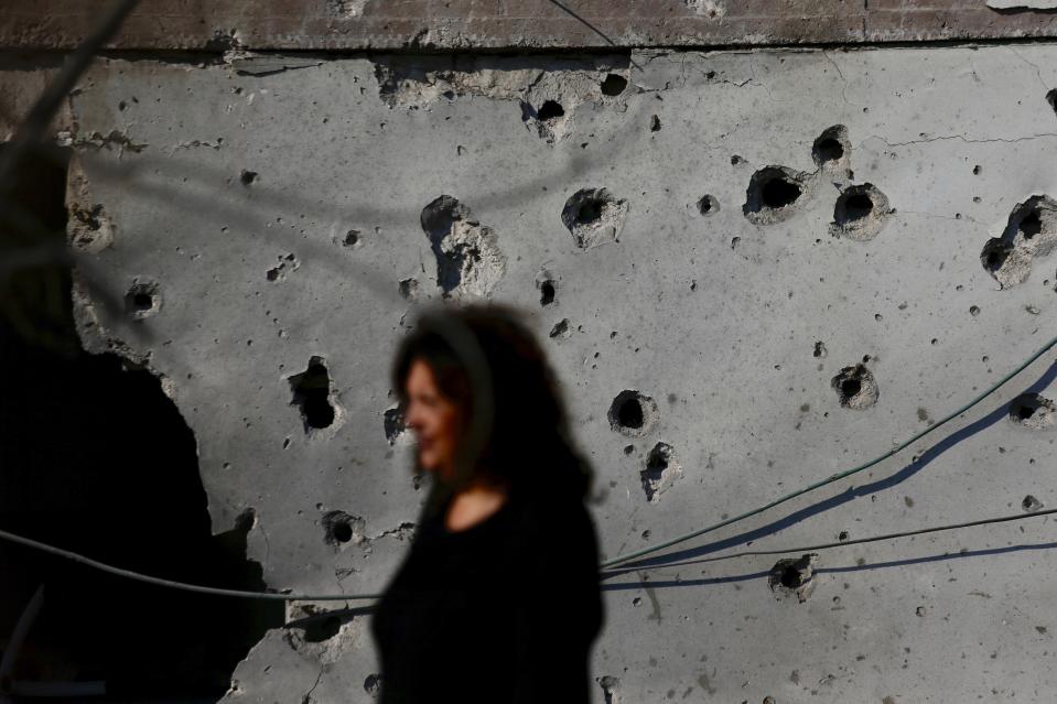 An Israeli woman walks in the yard of a house after it was hit by a rocket fired from Gaza Strip, in the southern Israeli city of Ashkelon, Israel, Tuesday, Nov. 13, 2018. (AP Photo/Ariel Schalit)