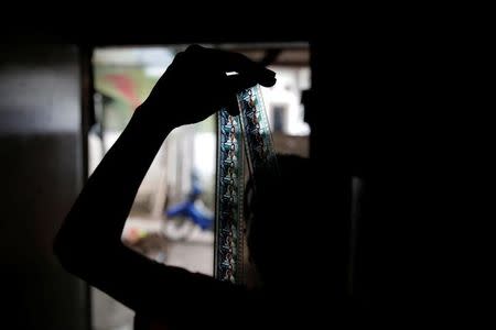 Kamaluddin checks a 35mm film strip at his workshop in Tangerang, Indonesia, March 11, 2017. REUTERS/Beawiharta/Files