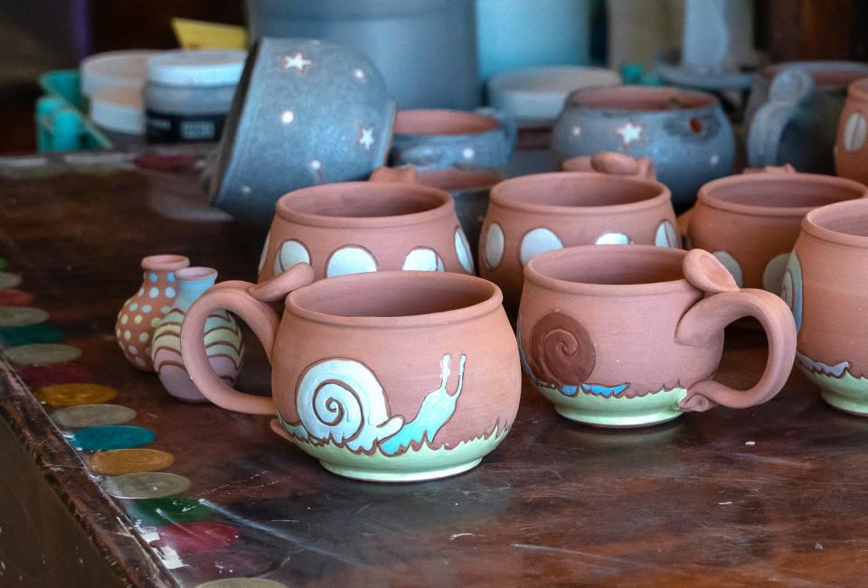 Nearly-finished ceramic mugs sit atop Mari Moore-Mosby’s tabletop in her studio. The Springfield artist, who is also a physical therapist, adds thumb tabs to make the mugs easier to hold.